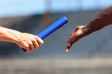 Image of a relay race with one athlete passing the baton to another