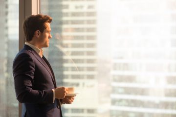 Man looking pensively out of office window.
